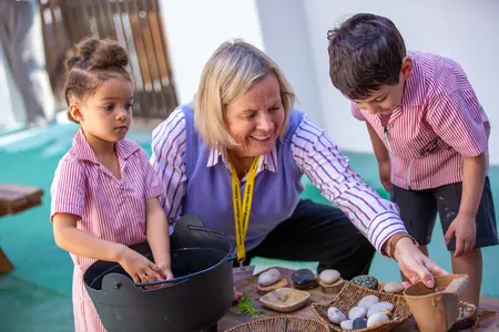 Children learning about stones in the DESS garden helped by the Lower School Teacher.