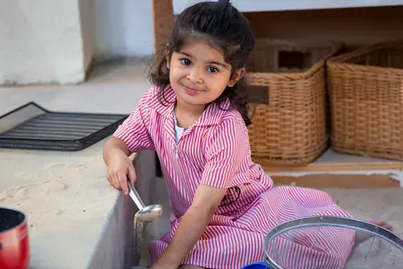 Lower School Girl sitting down playing with sand