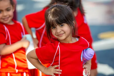 Lower School Girl smiling happily holding a Water Bottle attending a sports activitiy