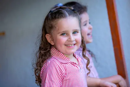 Lower School Girl in plats smiling happily